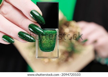 Female hands with green manicure hold a gift box for New Year and Christmas.