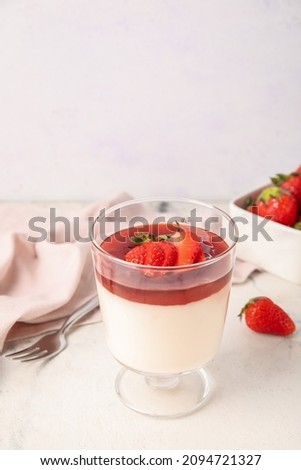 Glass with tasty homemade strawberry panna cotta on light background