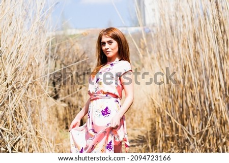 Beautiful young woman, in a beautiful dress on the background of a beautiful summer landscape 