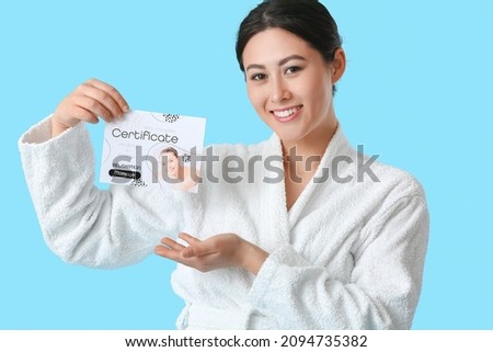 Young Asian woman with gift certificate for massage on color background