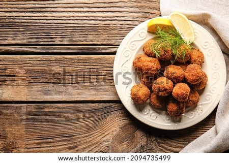 Plate with tasty cod cutlets with lemon on wooden background