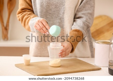 Woman preparing baby milk formula in kitchen Royalty-Free Stock Photo #2094738268