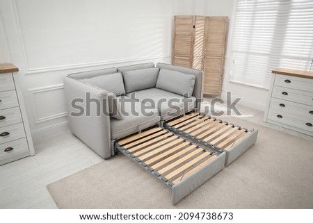 Stylish room interior with sleeper sofa near white wall. Additional place for guest Royalty-Free Stock Photo #2094738673