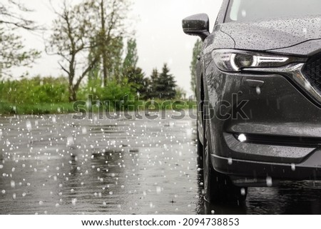 Modern car parked outdoors on rainy day with hail Royalty-Free Stock Photo #2094738853