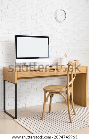 Modern workplace with computer near brick wall