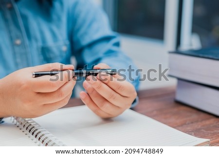 woman holding a pen sitting on a desk writing