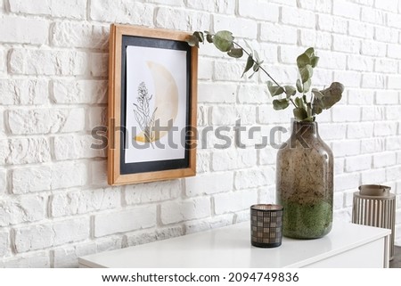 Vase with candle on shelf near brick wall