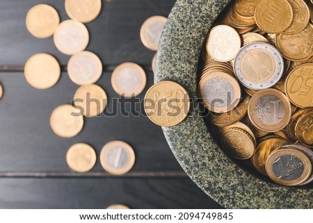 Bowl with golden coins on dark wooden background