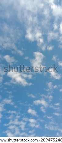 Cloudy blue sky background, vertical picture. Beautiful blue sky with big and tiny soft fluffy clouds after raining. Elegant cloudy blue sky wallpaper background. Vertical image. Texture background