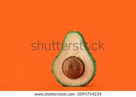 Mexican pinata in shape of avocado on orange background