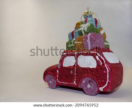 a Christmas tree toy in the form of a pink shiny car with gifts loaded on top is depicted on a gray background. space for copying. rear view