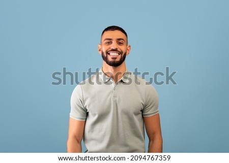 Portrait of happy arabic guy smiling at camera over blue studio background, copy space. Handsome middle-eastern young man in casual showing positive emotions Royalty-Free Stock Photo #2094767359