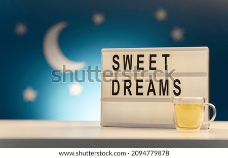 sleeping and bedtime concept - close up of customizable light box and cup of relaxing herbal tea over moon and night stars on blue background