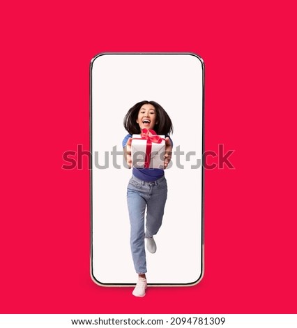 This Gift Is For You. Portrait Of Cheerful Excited Asian Woman Holding In Hands And Giving Present Box Package To Camera, Running Coming Out Of Big Smartphone Screen. Holidays Greeting, Celebration Royalty-Free Stock Photo #2094781309