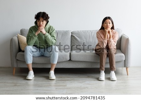 Family conflict, divorce, breakup concept. Stubborn young Asian couple sitting on opposite sides of couch in silence after fight, indoors. Offended millennial man and woman ignoring one another Royalty-Free Stock Photo #2094781435