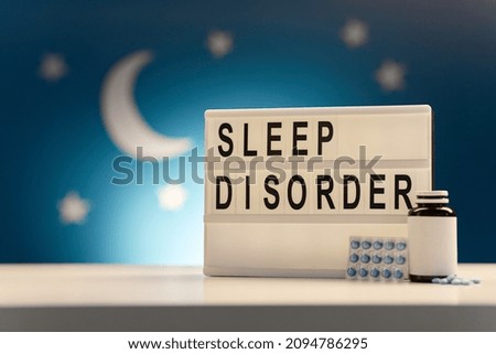 bedtime and medicine concept - close up of sleeping pills and customizable light box with sleep disorder words over moon and night stars on blue background