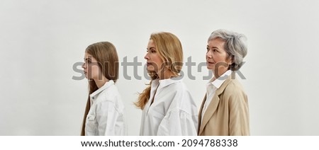 Side view of serious caucasian family of three female generations. Family generation change concept. Senior grandmother, adult mother and teenage granddaughter. White background in studio. Copy space Royalty-Free Stock Photo #2094788338