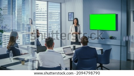 Diverse Office Conference Room Meeting: Successful Asian Businesswoman Uses Green Screen Chroma Key Wall TV Presenting Product to Group of Investors. e-Commerce Strategy. Wide Shot