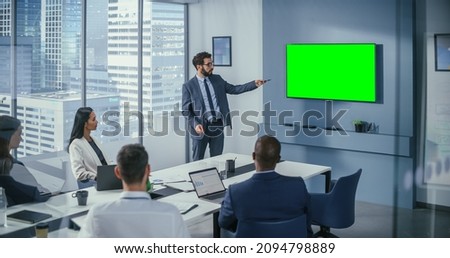 Office Conference Room Meeting Presentation: Motivated Caucasian Businessman Talks, Uses Green Screen Chroma Key Wall TV. Successfully Presenting a Product to Group of Multi-Ethnic Investors