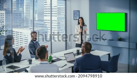 Office Conference Room Meeting Presentation: Asian Businesswoman Talks, Uses Green Screen Chroma Key Wall TV. Successfully Presenting a Product to Group of Diverse Investors. Businesspeople Applaud