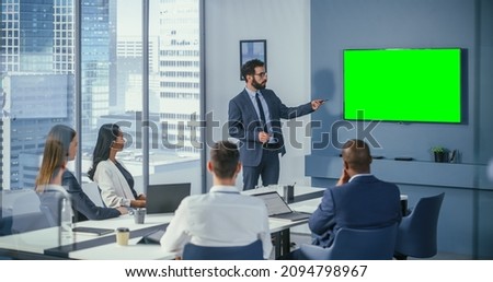 Diverse Office Conference Room Meeting: Male Project Manager Uses Green Screen Chroma Key Wall TV Presenting Opportunity for Group of Investors. e-Commerce Product Strategy. Medium Wide Shot