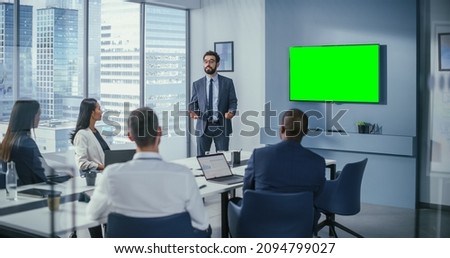 Office Conference Room Meeting Presentation: Businessman Talks, Uses Green Screen Chroma Key Wall TV. Successfully Presenting a Product to Group of Multi-Ethnic Investors. e-Commerce Strategy