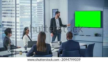 Office Conference Room Meeting Presentation: Handsome Businessman Talks, Uses Green Screen Chroma Key Wall TV. Successfully Presenting e-Commerce Product to Group of Multi-Ethnic Investors