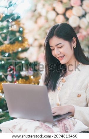 Portrait freelance business beautiful positive smile young asian woman online working with laptop computer at home in the living room indoors Decoration During Christmas x-mas and New Year holidays.