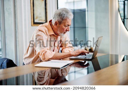 A smart senior student is sitting at home and typing homework on his laptop. Retraining concept. Royalty-Free Stock Photo #2094820366