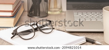 Online work at home. Glasses on a notepad in front of a laptop