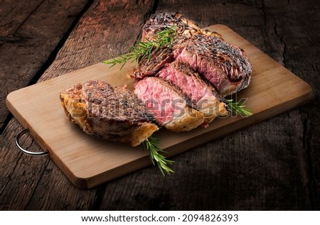 Fiorentina T-bone steak cut on rectangular wooden chopping board and vegetables isolated on white background Royalty-Free Stock Photo #2094826393