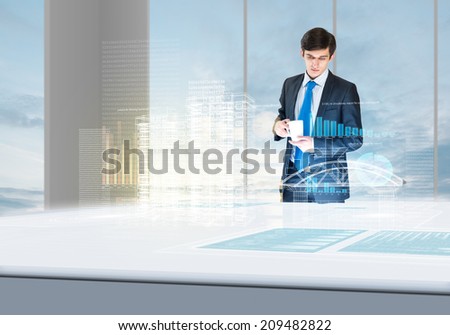 Young businessman looking at hologram of construction project