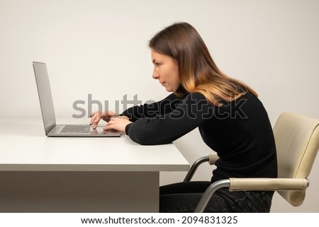 Young woman in slouching position sitting in office room, working with laptop Royalty-Free Stock Photo #2094831325