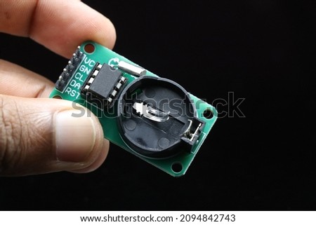 Real time clock module or RTC DS1302 module held in hand isolated on black background