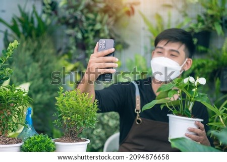 Asian male is taking photo of his houseplant in his houseplant small business shop for sale online.