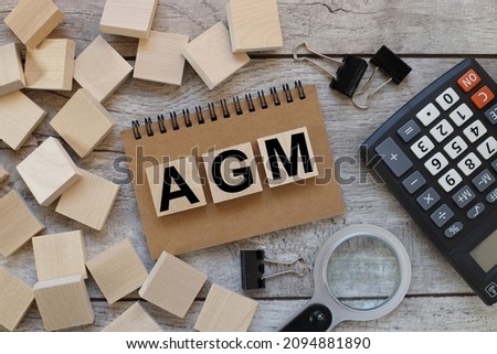 AGM Annual general meeting .Business concept. text on wood blocks on notepad on wood table