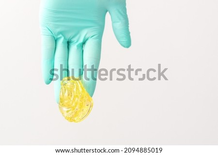Yellow sugar paste in hand master of depilation. Smiling beautician holding wax for depilation over white background. Concept epilation