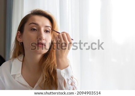 Natural clean face. Beauty Center. Woman carefully doing her makeup in front of the mirror for an evening date. 