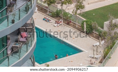 Swimming pool viewed from above timelapse, Aerial top view at Dubai marina. People swimming and relaxing on a chaise longue. Dubai, UAE