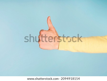 Thump up hand sign isolated on blue background. Copy space for your text Royalty-Free Stock Photo #2094918154