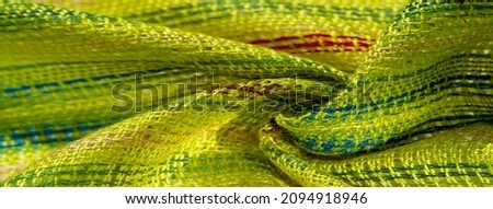 abric of light green color with stripes of red-blue-yellow lines, very light elastic knitwear, light sheen. texture background, pattern postcard