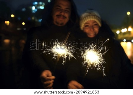 Couple with sparklers at night. Happy people enjoying fireworks outdoors                              