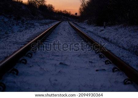 The railway running along Donetsk, along which trains with coal go. Against the background of dawn, the reflection of the red sun falls on the rails along which the first snow lies