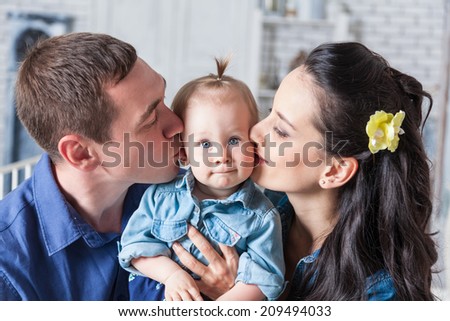 Lovely family together at home. Mother and father kissing his year-old daughter