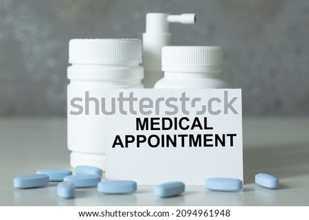 a card with the text MEDICAL APPOINTMENT on the table next to the white jars of medicine and scattered blue pills on the floor