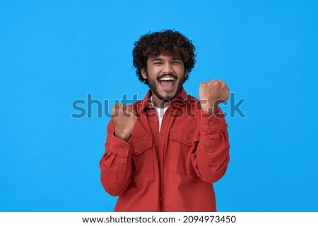 Excited happy young indian man winner looking at camera showing yes gesture feeling happy about betting lottery win, winning prize, getting new job celebrating victory isolated on blue background. Royalty-Free Stock Photo #2094973450