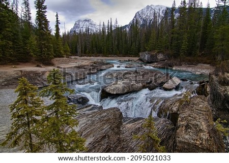 Typical Canadian lanscape featuring river, woods and snow-capped mountains Royalty-Free Stock Photo #2095021033