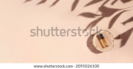 Banner of Perfume sample with yellow liquid on wooden tray lying on beige background with shadows above. Luxury and natural cosmetics presentation. Tester on woodcut in the sunlight. Shades and lights Royalty-Free Stock Photo #2095026100