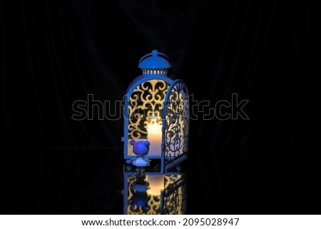 Little girl stands in front of a festive lantern with a candle