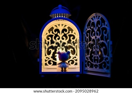 Little girl stands in front of a festive lantern with a candle